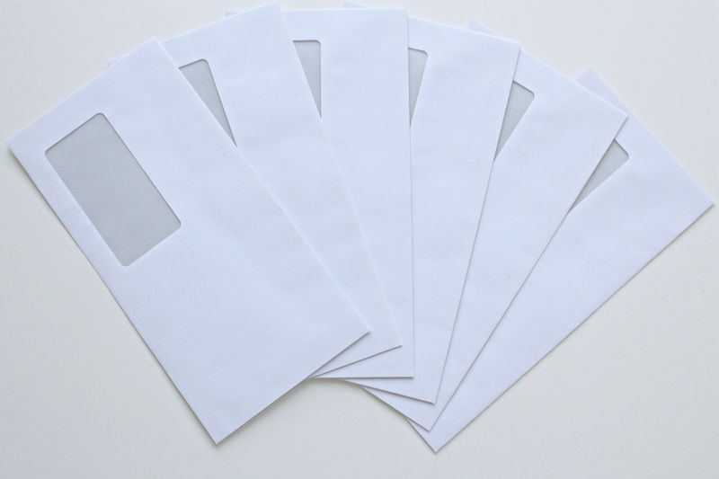 A set of white window envelopes fanned out on a flat surface, ready for mailing or office use.