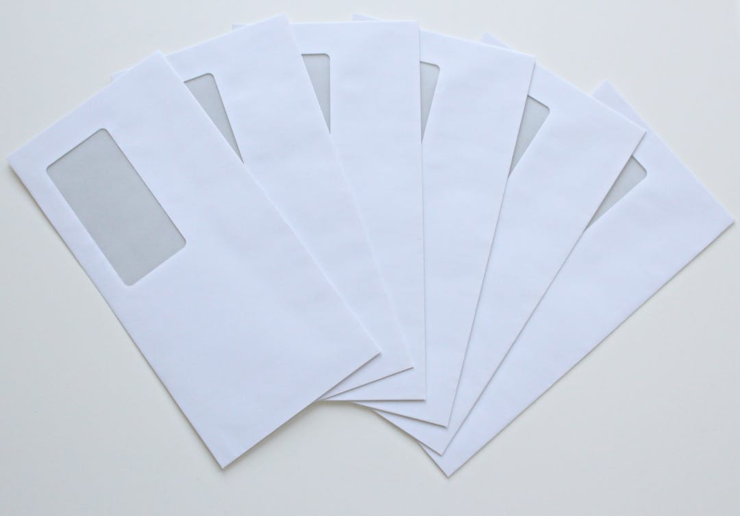 A set of white window envelopes fanned out on a flat surface, ready for mailing or office use.