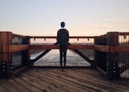 日落时分，一个人独自站在木桥上，俯瞰宁静的河流