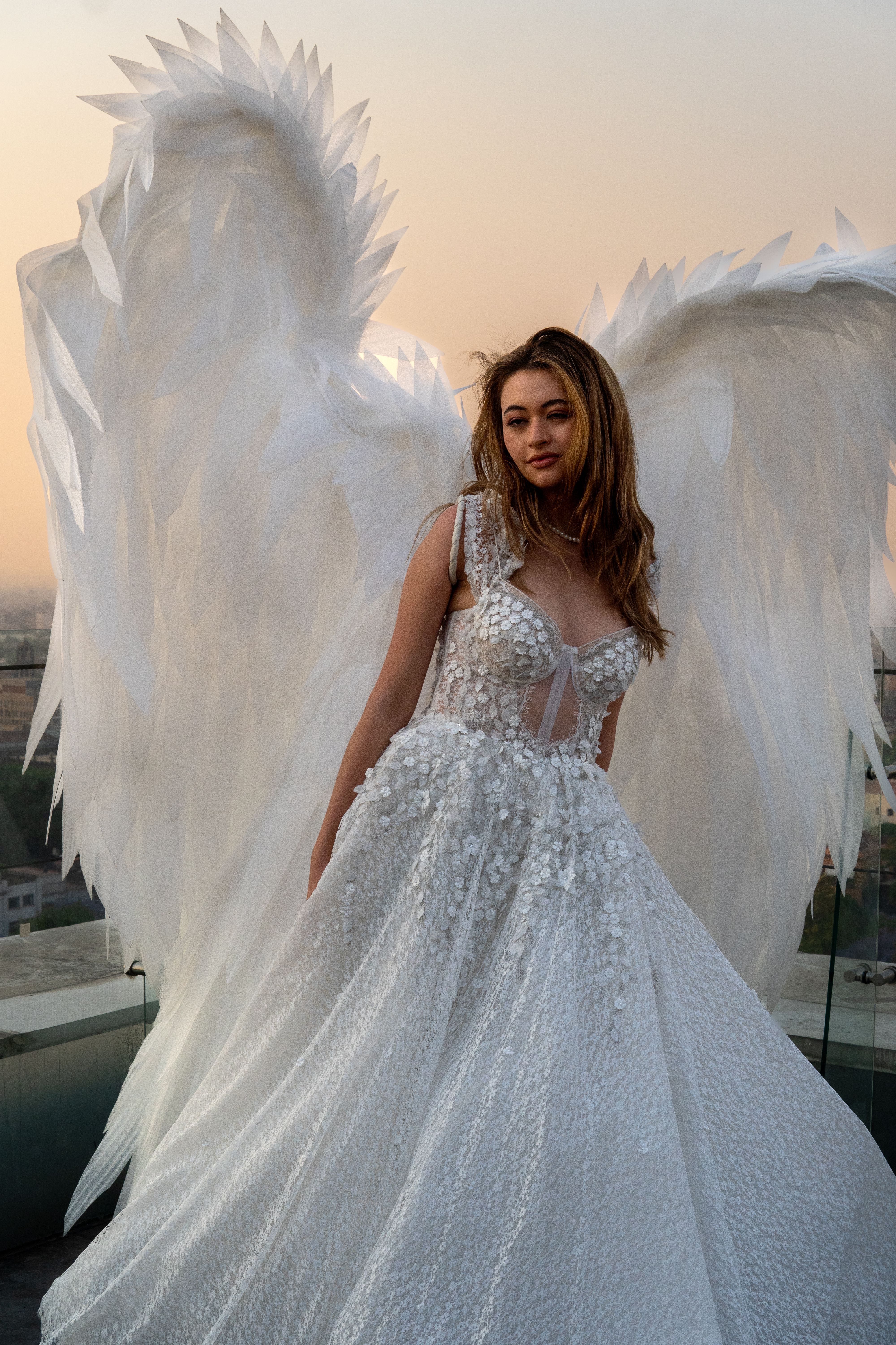 A stunning model in a wedding dress with angelic wings at sunset in Mexico City.
