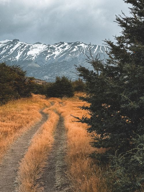 Free A picturesque dirt road winds through the Chilean Patagonian landscape with majestic mountains in the background. Stock Photo