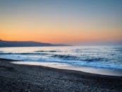 希腊海滩上，平静海浪映衬着美丽的日落，捕捉了大自然的宁静之美