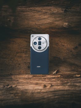 A modern smartphone with quad-camera on a textured wooden background.