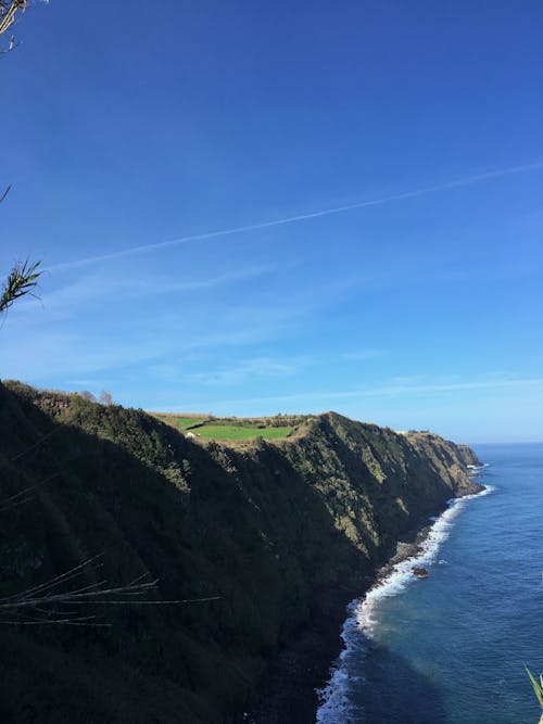 Foto Do Penhasco Ao Lado De Um Corpo D'água Sob O Céu Azul