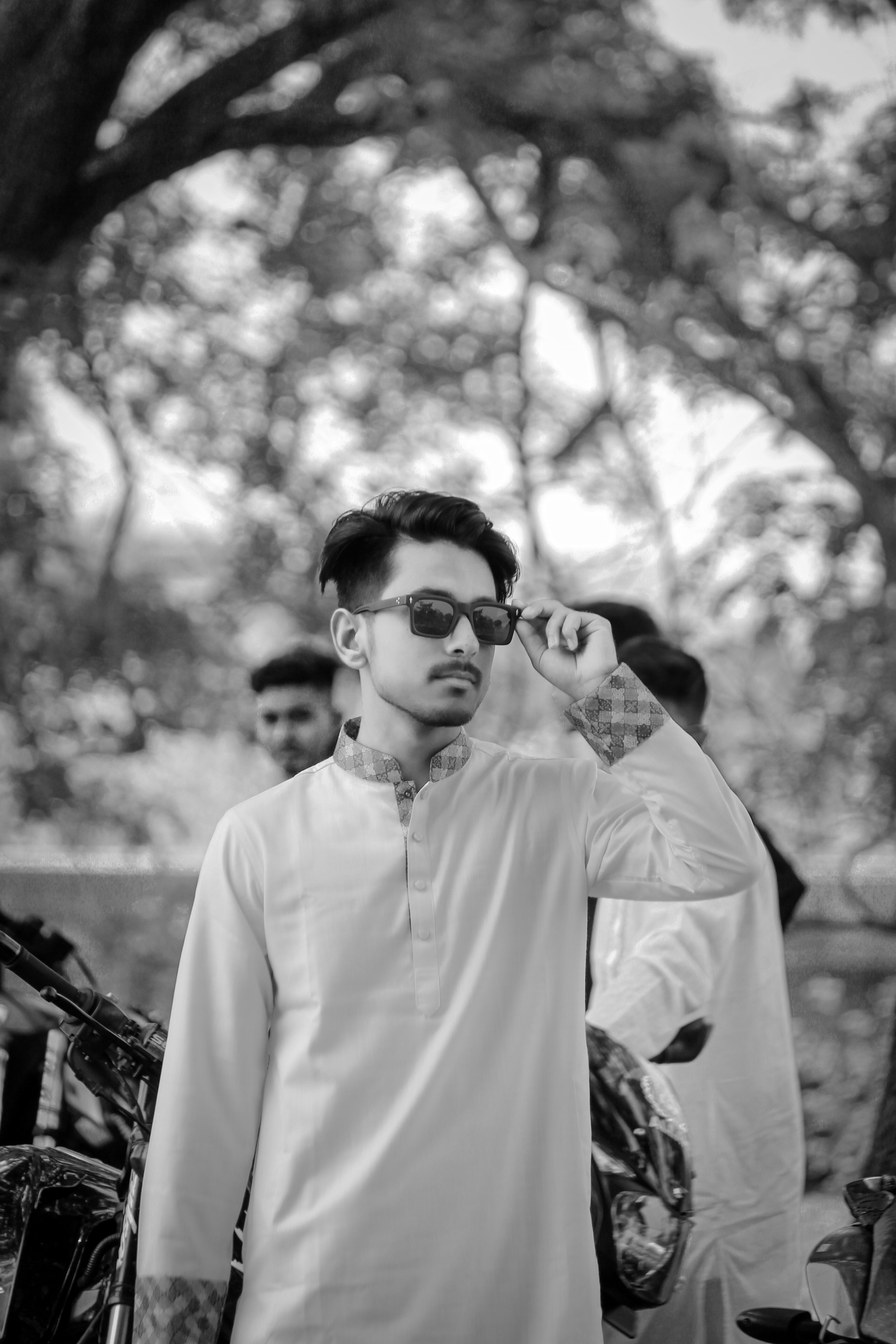 Young man wearing sunglasses and traditional kurta, set in a natural outdoor environment.