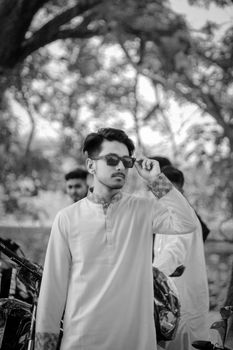 Young man wearing sunglasses and traditional kurta, set in a natural outdoor environment.