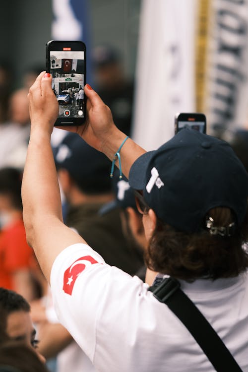 Free A person records a live event with a phone, capturing the vibrant atmosphere. Stock Photo