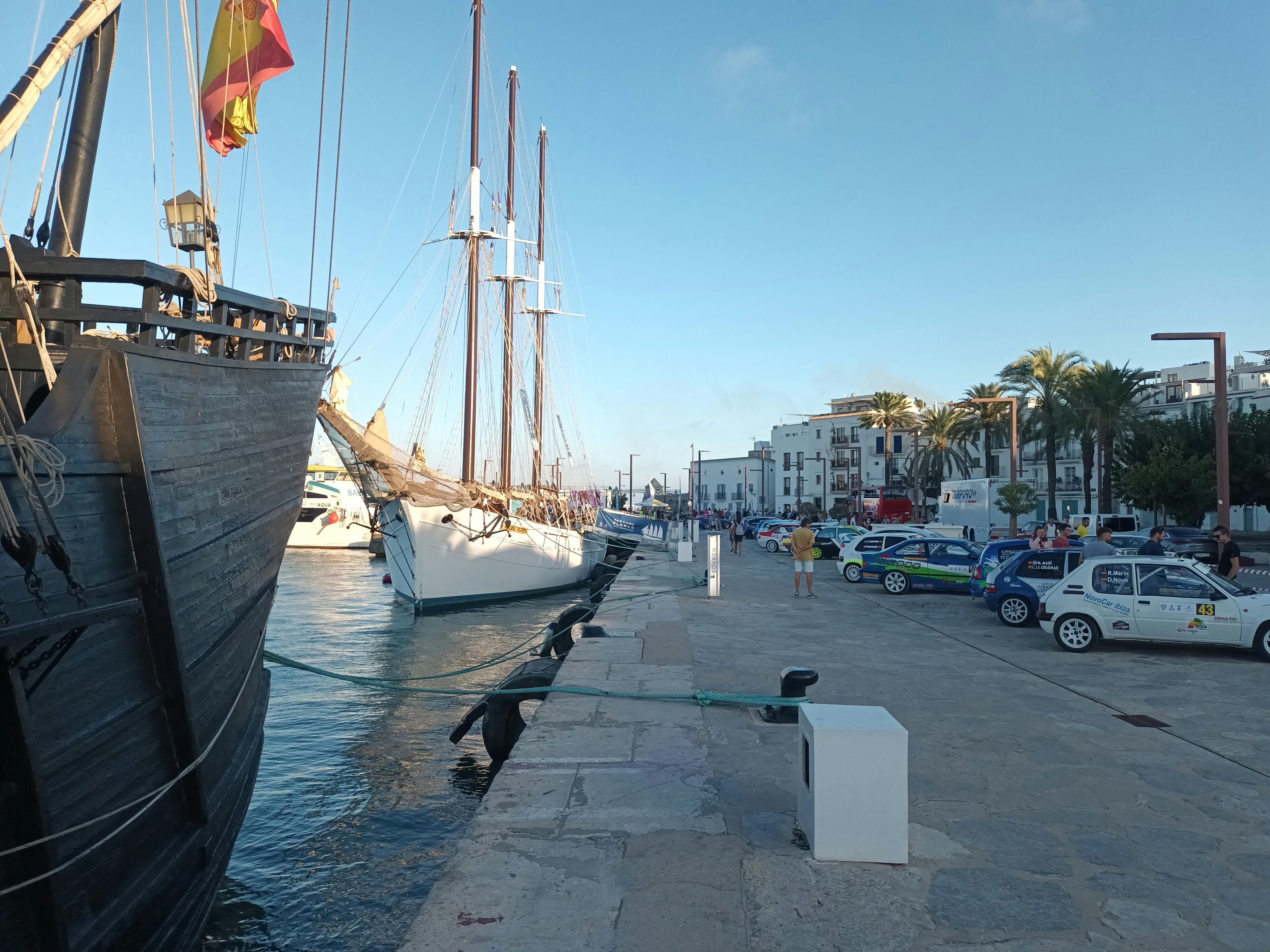 Explore the lively Ibiza harbor with moored boats, cars, and blue skies.
