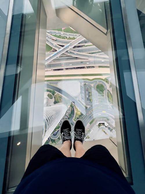 A person standing on an escalator with their feet on the glass