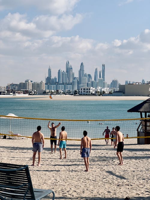 People playing volleyball on the beach with the city skyline in the background