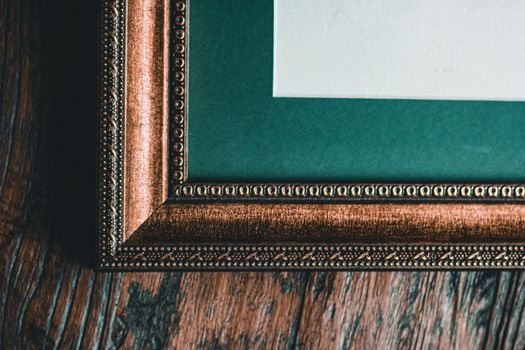 Close-up of an ornate vintage picture frame corner on textured wooden surface.