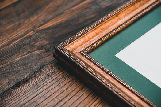 Close-up of a detailed antique wooden frame against a rustic wood backdrop, emphasizing vintage elegance.