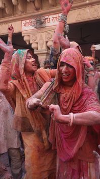 Vibrant Holi festival celebration with women covered in colorful powder, expressing joy and laughter.