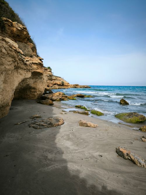 Free Serene rocky shoreline with ocean waves under clear skies. Stock Photo