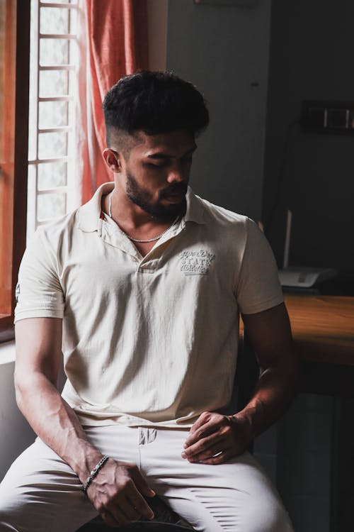 A man sitting on a chair in a white polo shirt