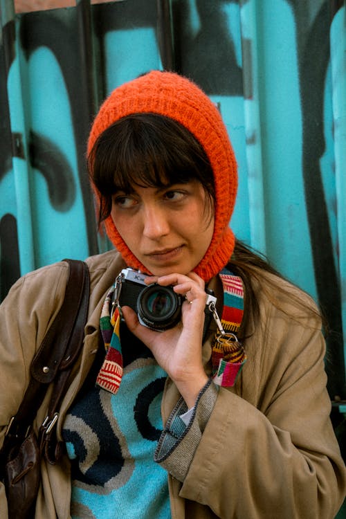 A woman with a camera in front of a graffiti wall