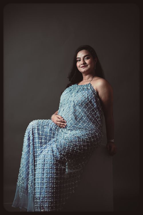 Free Studio portrait of a pregnant woman in a blue dress, smiling and posing. Stock Photo