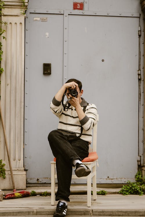 A man sitting on a chair taking a picture of himself