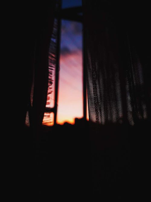 Free Dark mesh curtains frame a vibrant sunset view. Perfect for artistic and moody themes. Stock Photo