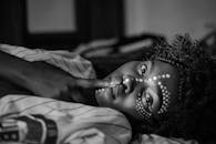 这是一张女人的黑白特写肖像，她脸上涂着油漆，留着卷发，正在做手势