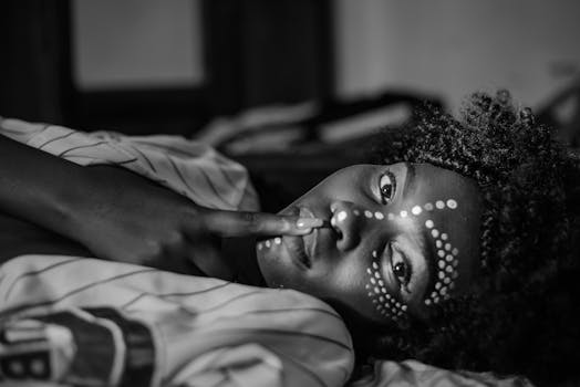 这是一张女人的黑白特写肖像，她脸上涂着油漆，留着卷发，正在做手势