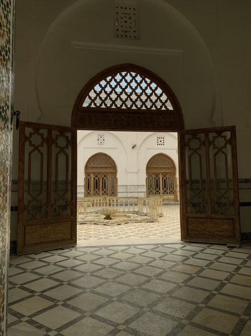 Free Elegant view through an arched wooden doorway leading to a historical courtyard. Stock Photo