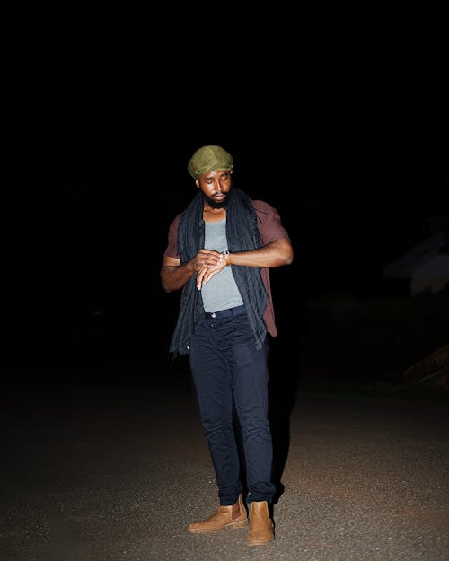 A man standing in the dark wearing a hat and scarf