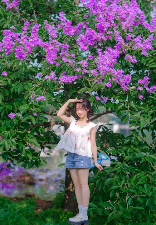 A girl standing in front of a tree with purple flowers