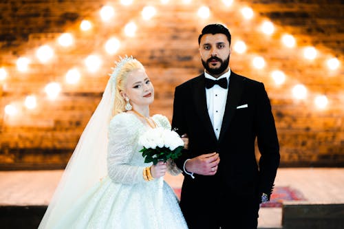 A bride and groom standing in front of a lighted stage