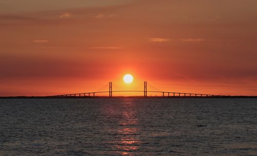 Free A breathtaking sunset over a long bridge spanning the ocean, casting a warm glow. Stock Photo