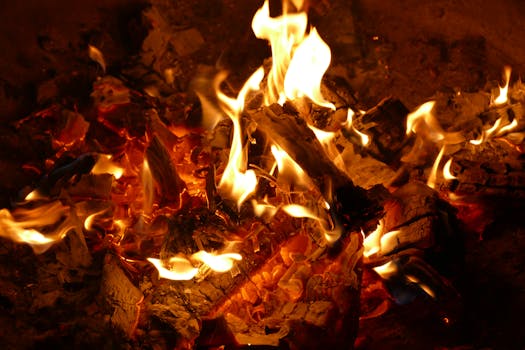 A close-up image of a campfire with burning wood and vivid flames at night.
