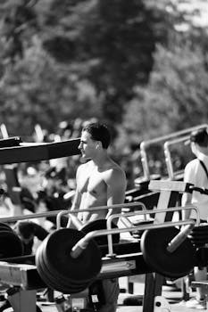 Black and white image of a man working out at an outdoor gym, focused and determined.
