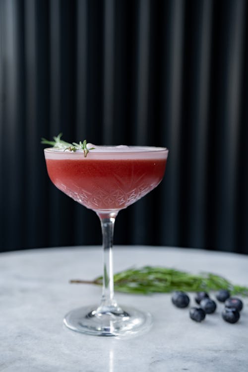 A cocktail with a garnish of rosemary and berries