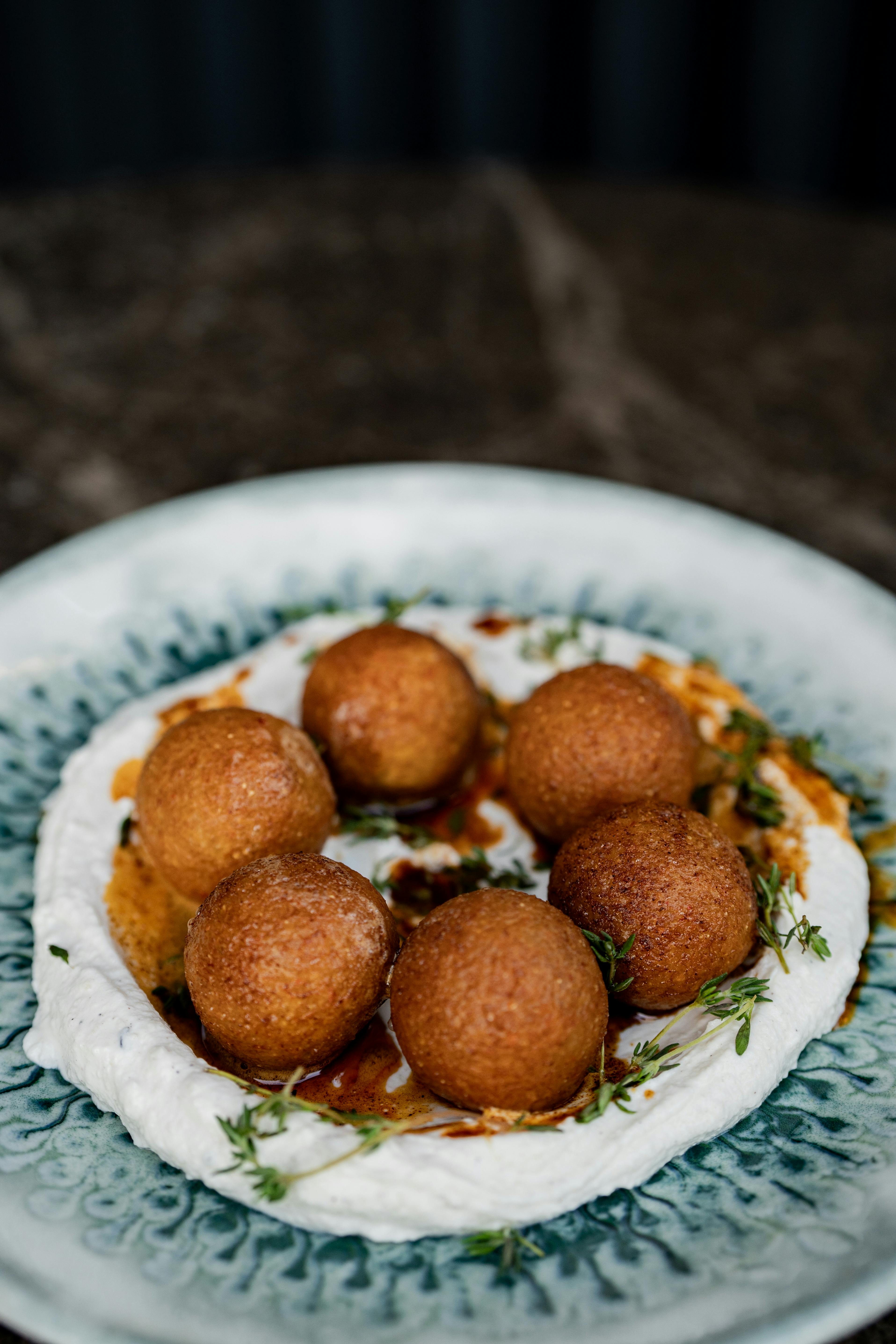 a plate topped with fried balls and yogurt