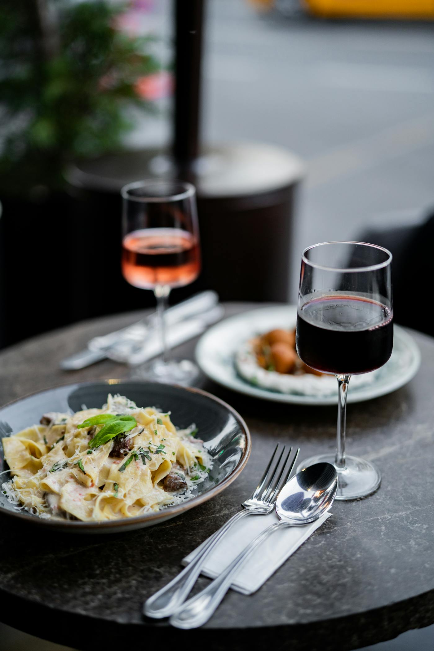 Piatto di pasta elegante con bicchiere di vino rosso su tavola apparecchiata