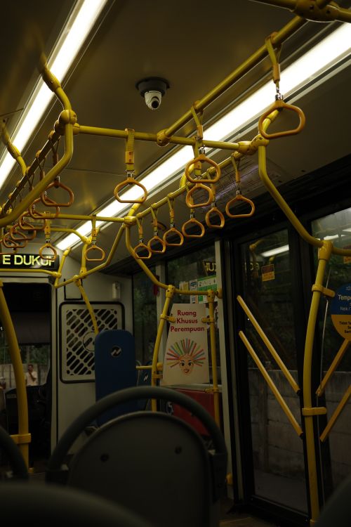 Free Interior view of a public bus focusing on yellow handrails and seating arrangement. Stock Photo