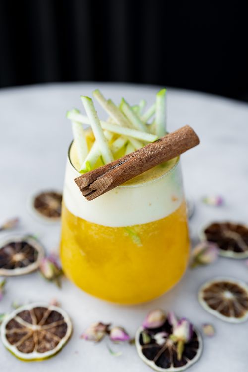 Free A vibrant fruit mocktail garnished with apple sticks and cinnamon, perfect for refreshment. Stock Photo