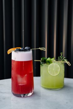 Vibrant cocktails featuring fresh fruit garnishes on a marble table, perfect for summer refreshment.