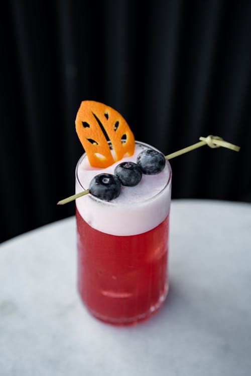 A cocktail with blueberries and orange slices