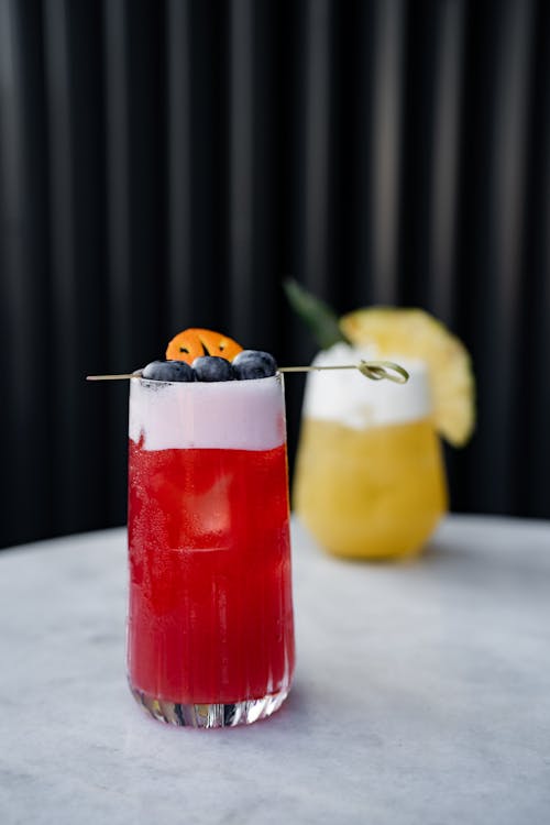 A cocktail with a blueberry and orange garnish
