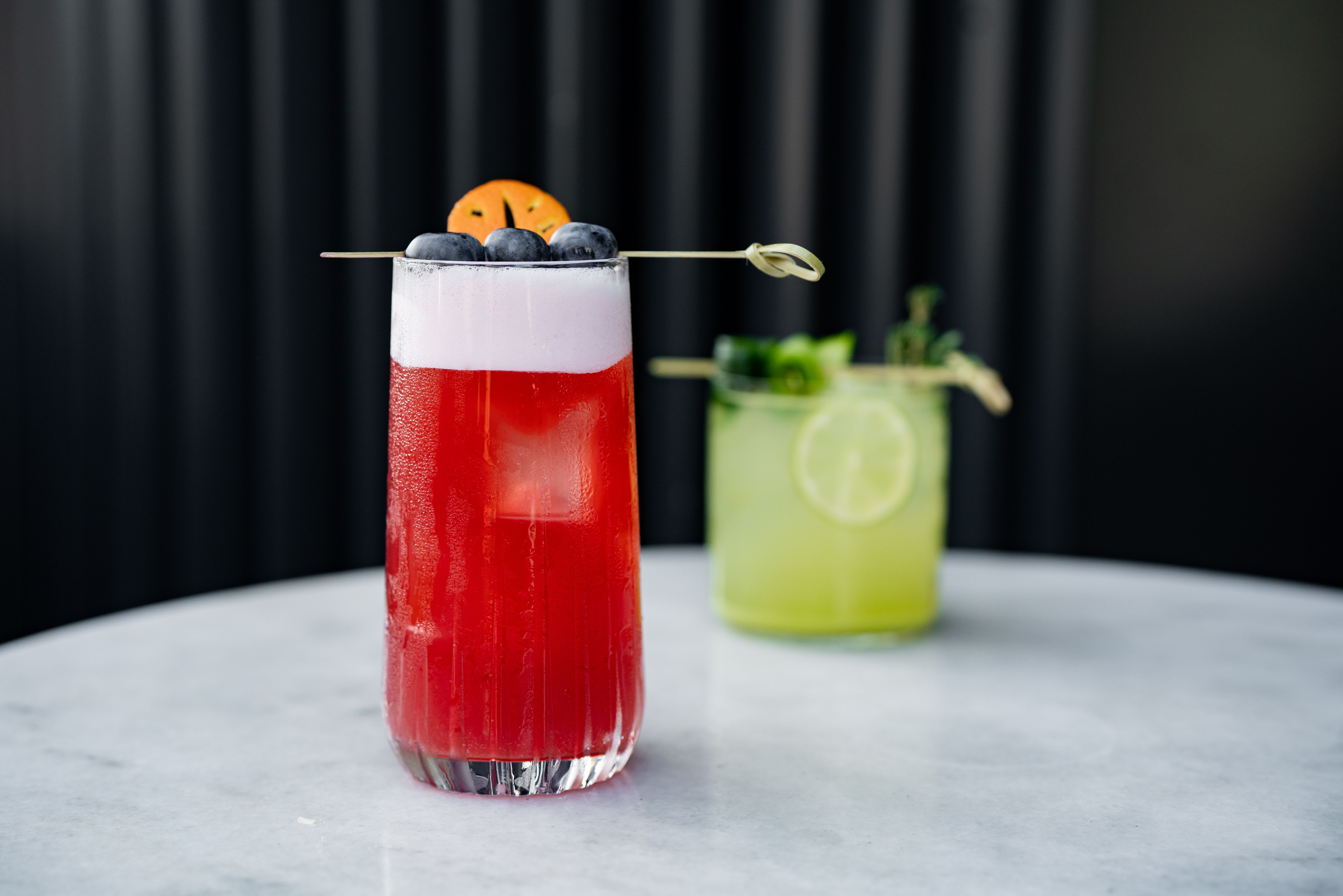 A vibrant red cocktail with berry garnish on a marble table in İstanbul.