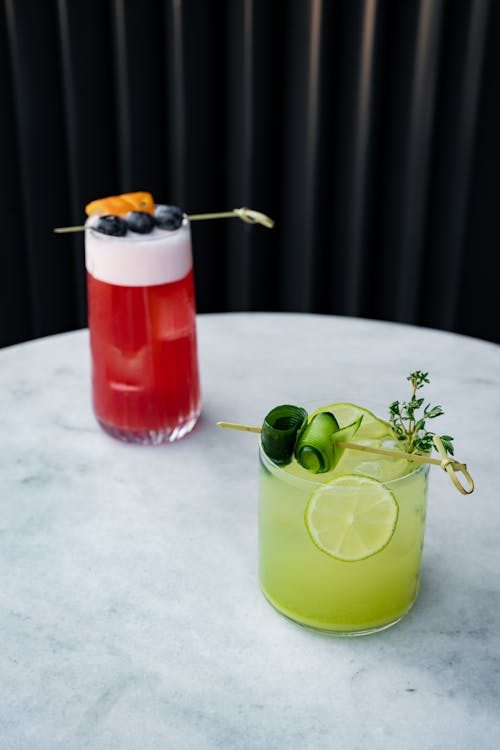 Two cocktails are sitting on a table with a lime