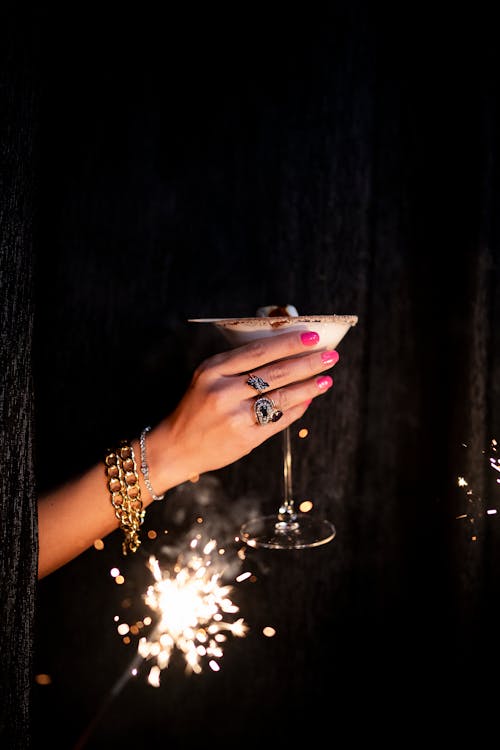 A woman's hand holding a martini glass with sparklers