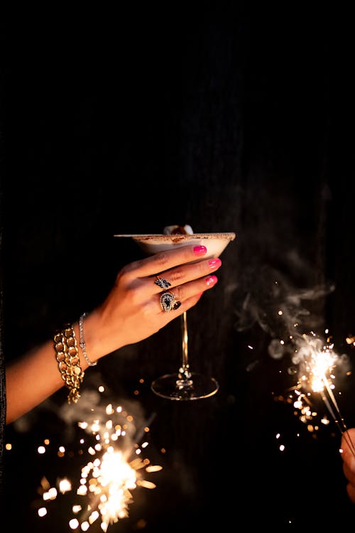 A woman holding a martini glass with sparklers
