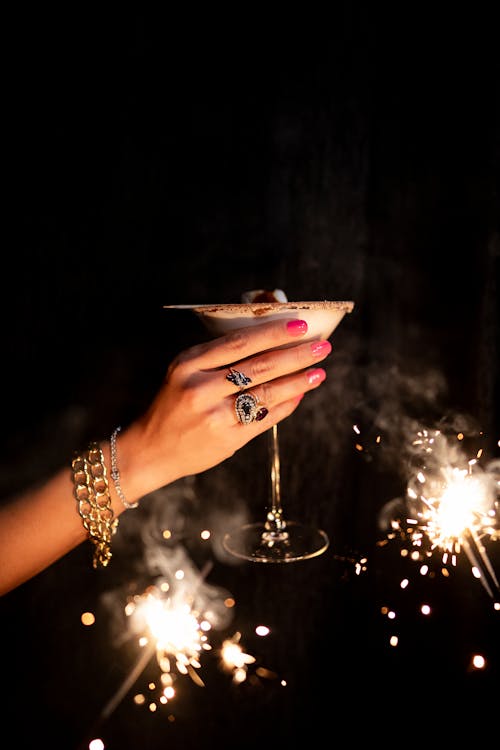 A woman's hand holding a martini glass with sparklers