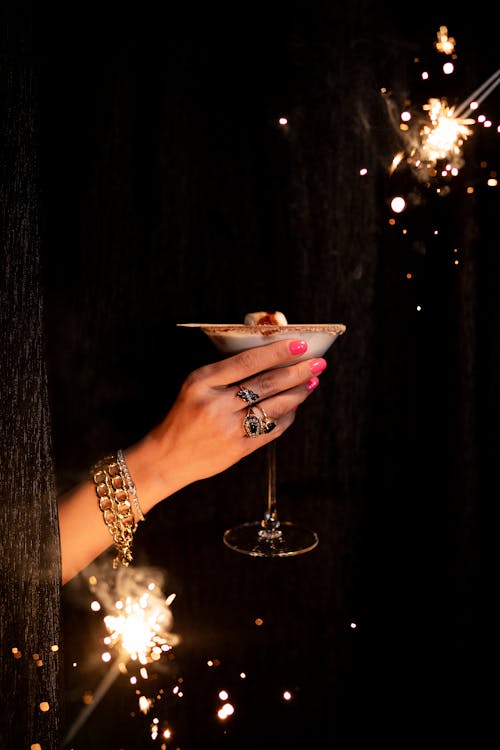 A hand holding a martini glass with sparklers