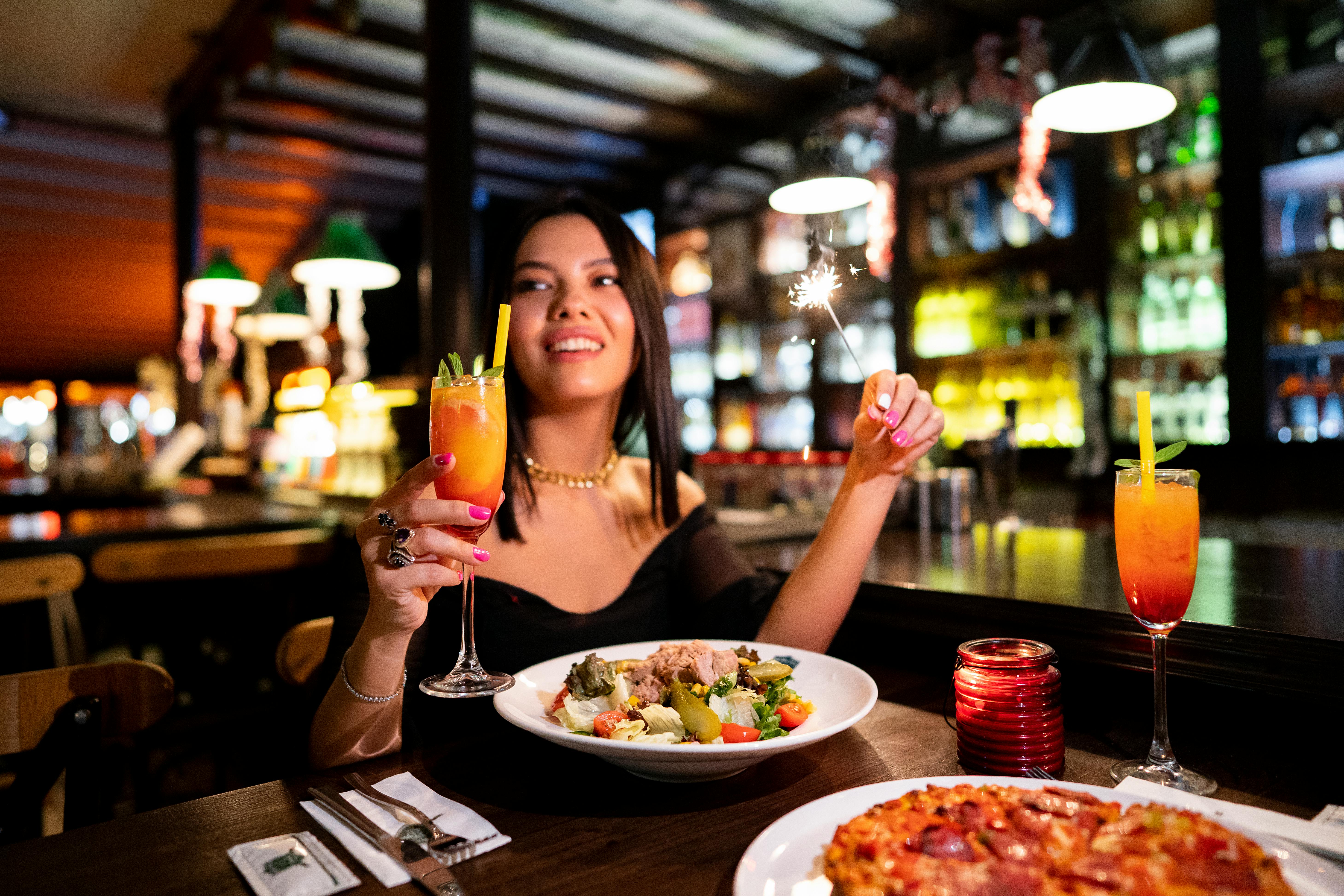 a woman holding a glass of wine and a pizza