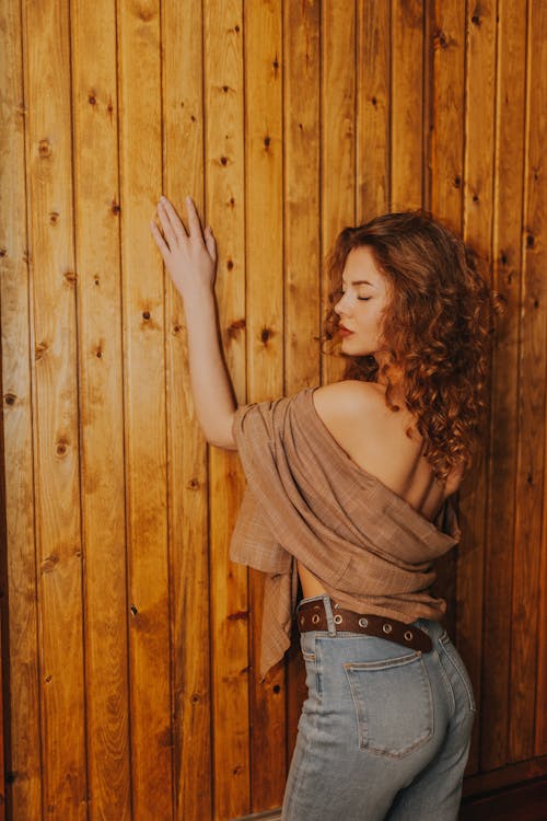 A woman leaning against a wooden wall