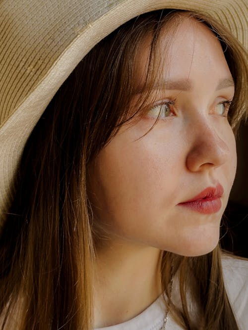 A woman wearing a straw hat and looking off to the side