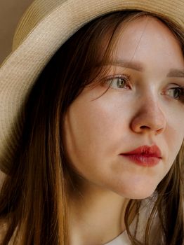 Close-up portrait of a woman wearing a straw hat with a thoughtful expression.